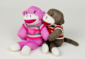 A pair of sock monkeys holding eachother
