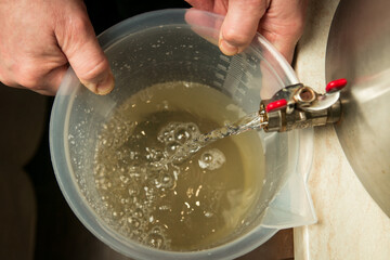 The process of making limoncello lemon liqueur at home. The man pours the prepared sugar syrup into...