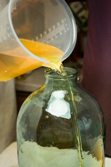 The process of making limoncello lemon liqueur at home. A man pours filtered alcohol infused with...