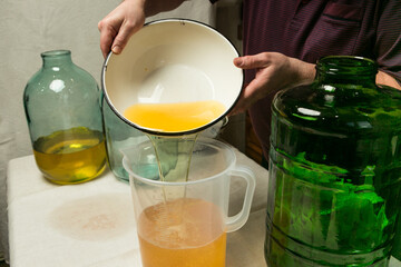 The process of making limoncello lemon liqueur at home. The man drains and strains the alcohol...