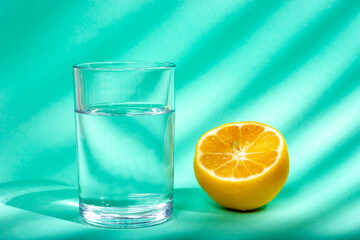 A glass of water and lemon in the sunlight. Beautiful curly shadow.
