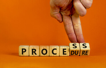 Process or procedure symbol. Businessman turns wooden cubes, changes a word 'process' to 'procedure'. Beautiful orange background. Business and process or procedure concept. Copy space.