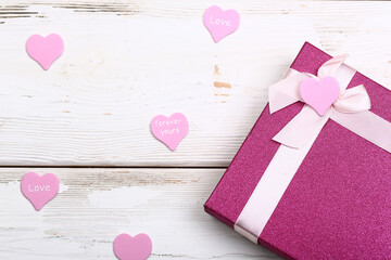 Valentine day design. Pink gift box with bow on white wooden background