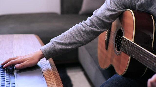 家のソファに座ってギターを練習する日本人の男性