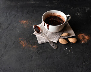 Obraz na płótnie Canvas Hot chocolate with almonds in a white cup with a spoon on a black background with space for text. Top view 