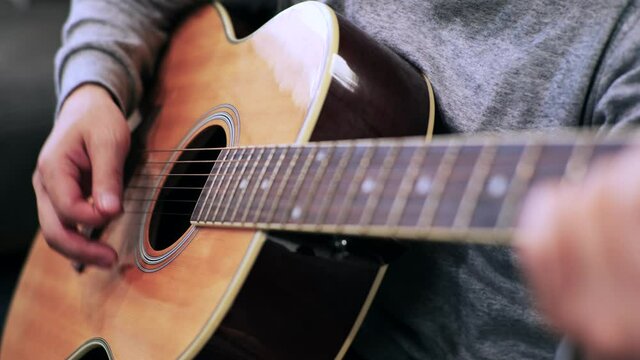 家のソファに座ってギターを練習する日本人の男性