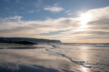 looking down Borth beach with smooth reflective sands beautiful blue sky's and groyne makers placed along the shore to warn ships and boats of danger