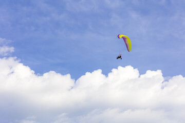paraglider with engine flying very high along the sky clouds