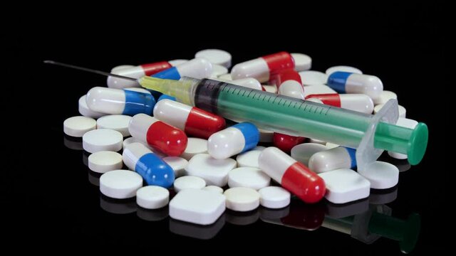 Pills, drugs, supplements, vitamins rotating on a black background. White medical pills, red and blue capsules rotating in 4K. Concept: Opioid crisis, drug addiction. 