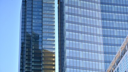 Obraz premium Glass facade of the buildings with a blue sky. Skyscrapers in the business city center.. Background of modern glass buildings. 