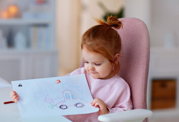 cute toddler baby girl showing her drawing, that was done with colour pencils