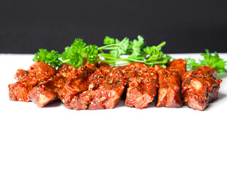 Uncooked raw marinated style pork belly chops on a white background with coriander leafs. Korean style marinade over the slices. Meat industry product