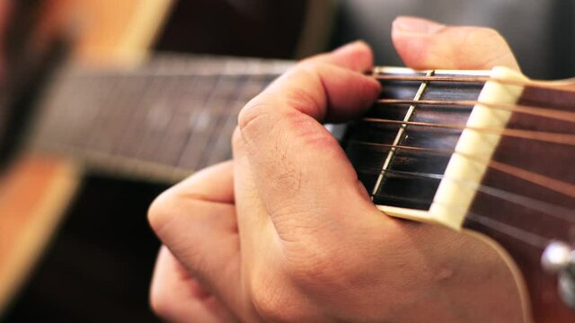 家のソファに座ってギターを練習する日本人の男性