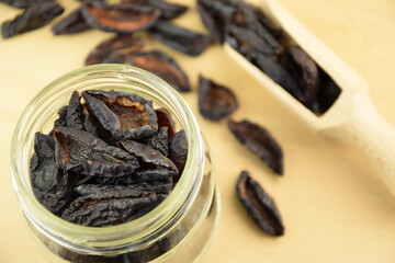 Prunes, dried plums fruits on jar, spoon, on wooden background, healthy fruits