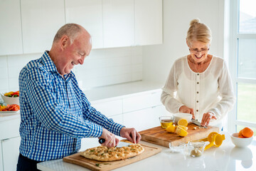 Senior couple cutting food on kitchen island at home