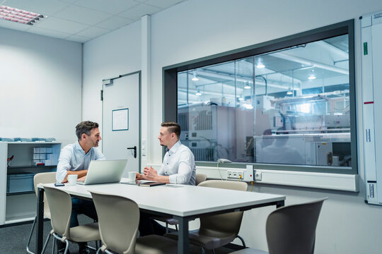 Business People With Laptop Having Board Meeting In Factory