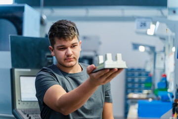 Young engineer holding model while standing at industry