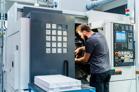 Technician repairing machine while standing at industry