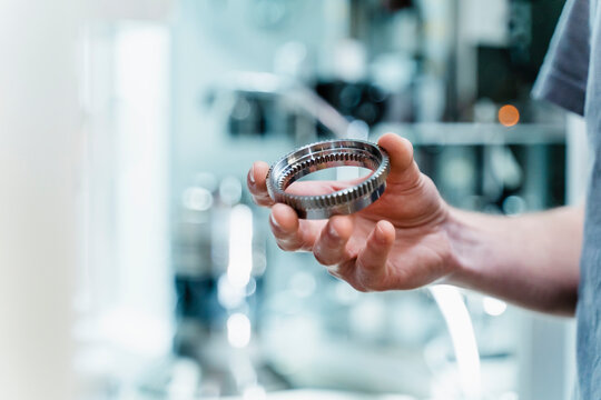 Engineer holding circular machine part at industry