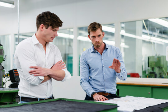 Businessman explaining floor plan to male engineer while working in factory