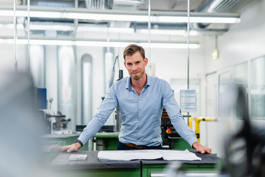 Smiling male entrepreneur with floor plan in industry