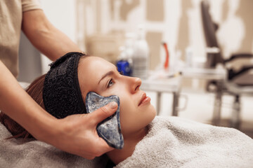 Woman receiving facial massage in beauty salon.