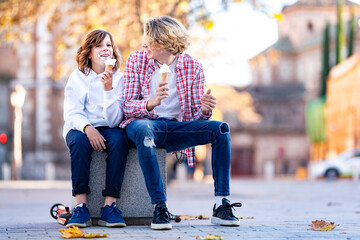 Smiling boy and man eating ice cream while sitting on bench