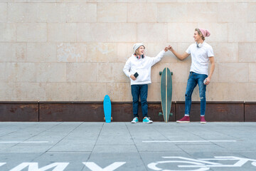 Friends giving fist bump while standing by skateboards on footpath