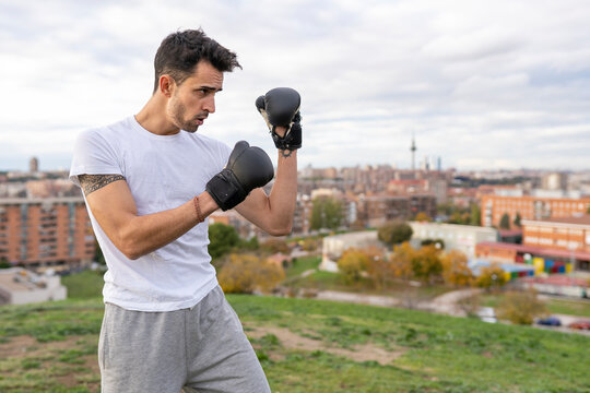 Male acrobat practicing boxing on hill in city