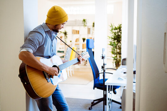 Musician playing guitar while standing at studio