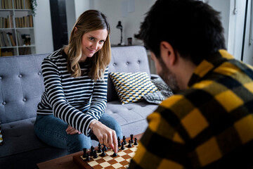 Woman and man playing chess at home
