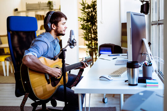 Musician singing while playing guitar at recording studio