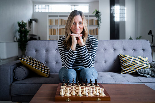 Portrait of woman sitting on sofa in front of chess board