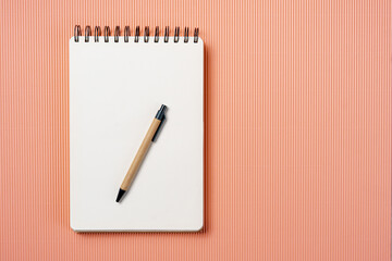 School notebook on a paper champagne background, spiral notepad and craft cardboard pen