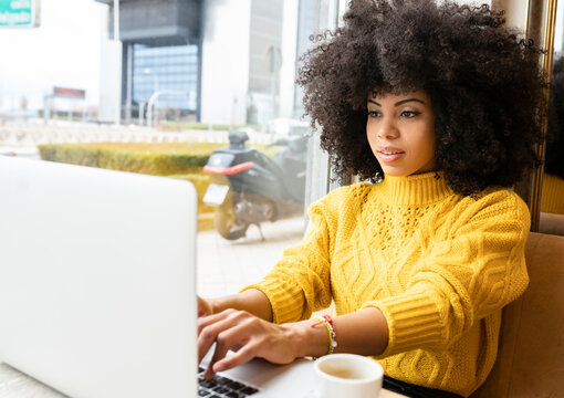 Young woman working on laptop while sitting at cafe