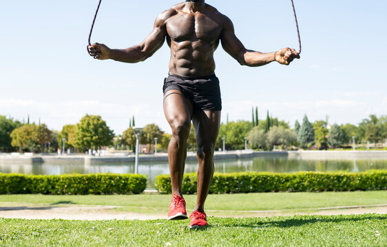 African male athlete doing skipping exercise in park on sunny day