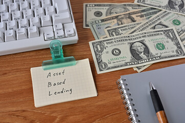 On the desk there were bills, a keyboard, and a word book with the word Asset Based Lending written on it.