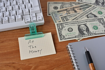 On the desk there were bills, a keyboard, and a word book with the word at the money written on it.