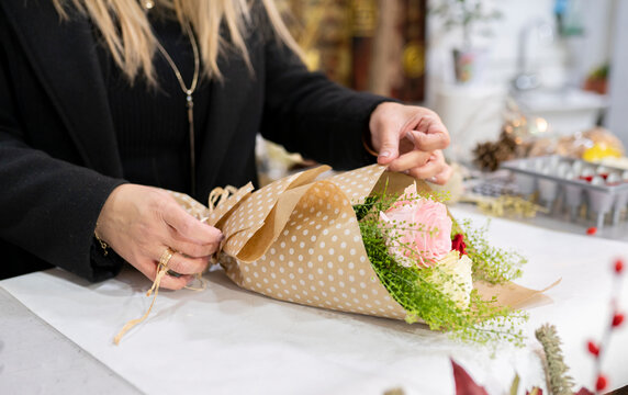 Florist wrapping bouquet with paper at flower shop