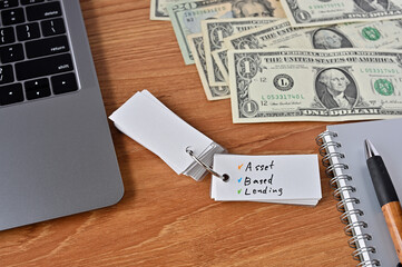 On the desk there were bills, a laptop, and a word book with the word Asset Based Lending written on it.