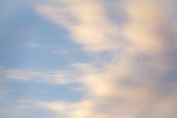 Pre sunset moody white wispy clouds in a blue sky with yellow tones