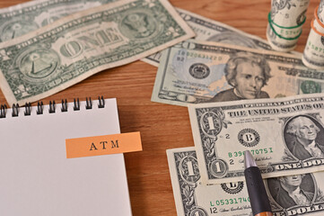 On the desk there are bills, a notebook, and a sticky note with the word ATM written on it. It was an abbreviation for the financial term at the money.