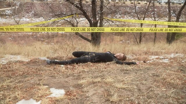 Pretty female jogger, crime victim,  found deceased in grass field camera ZOOMS OUT to reveal scene