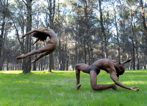 Two professional dancers wearing futuristic goggles performing in middle of forest