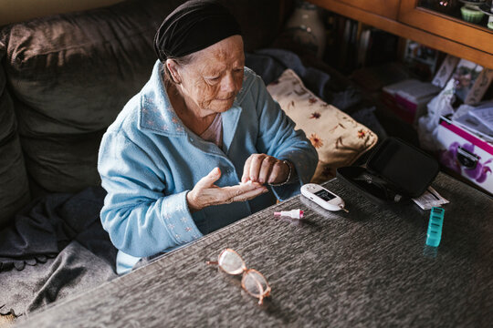 Elderly woman being tested for diabetes in living room at home