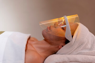 Young woman wearing mask during rejuvenating treatment at beauty spa