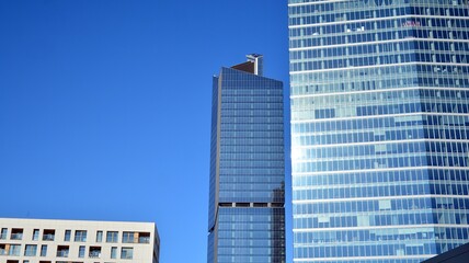 Fototapeta premium Glass facade of the buildings with a blue sky. Skyscrapers in the business city center.. Background of modern glass buildings. 