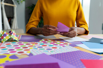 Origami artist sitting in studio folding colorful paper