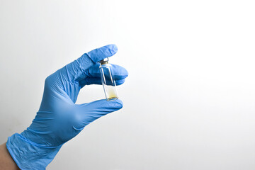 A blue-gloved hand holds the vials of the vaccine. copies a space. Copy space.