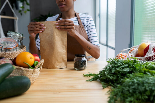 Woman with apron in kitchen , unpacking freshly bought organic fruit and vegetables